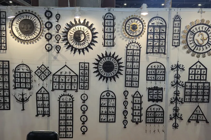 Black cut-metal wall hangings shaped as suns, windows and houses on a white stand wall.