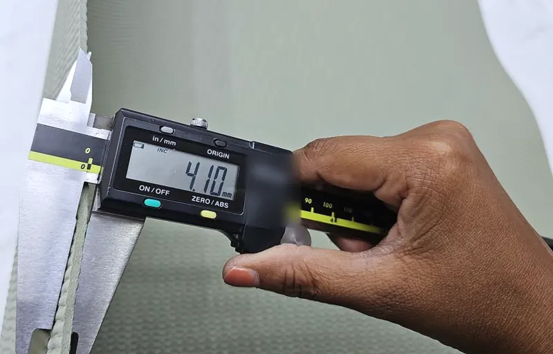 A digital caliper reading 4.10 mm on the edge of a sage-green exercise mat.