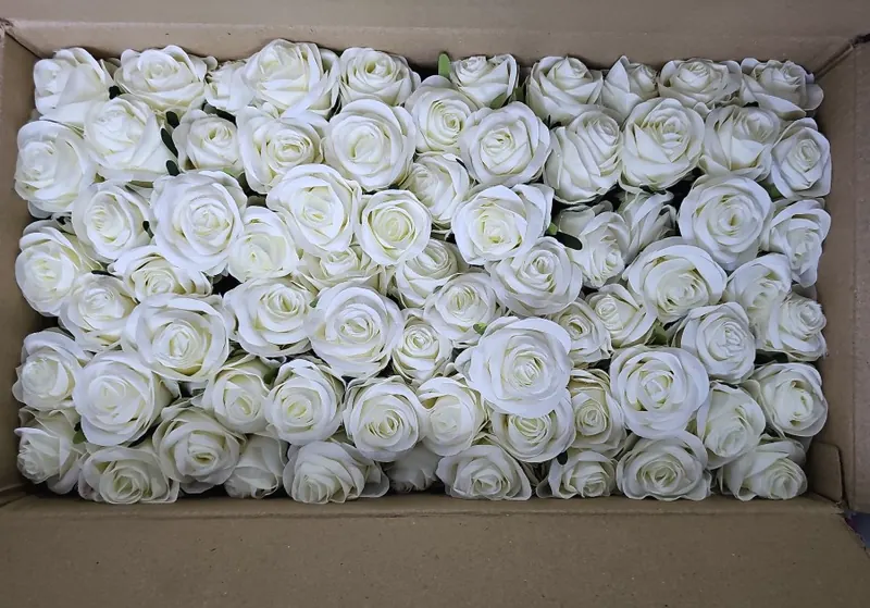 An open carton packed tightly with cream artificial rose heads.