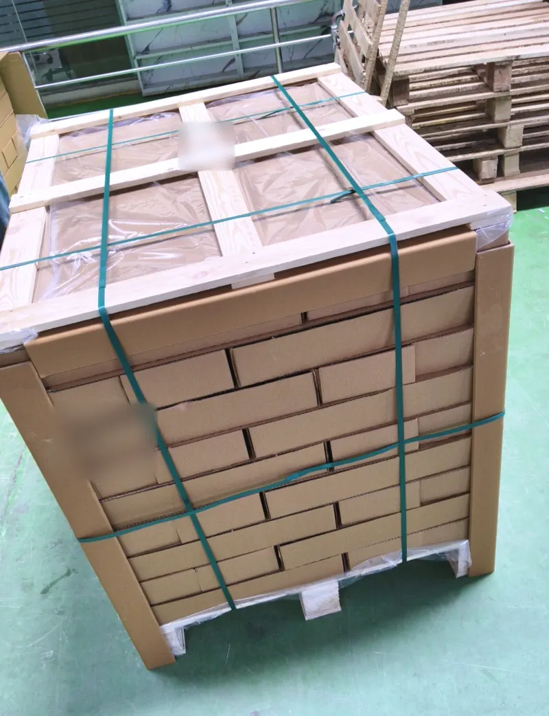 An export pallet of cartons protected with corner boards, a timber top frame and green strapping.