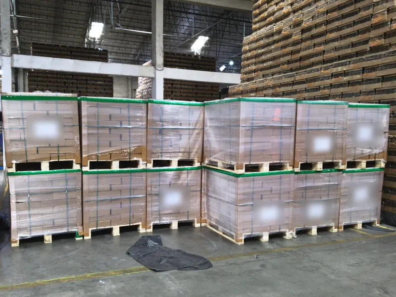 Two tiers of stretch-wrapped, strapped cartons on wooden pallets in a warehouse, ready for loading.