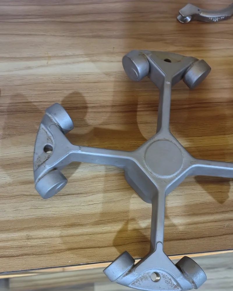 A four-armed aluminium spider casting on a wooden table.